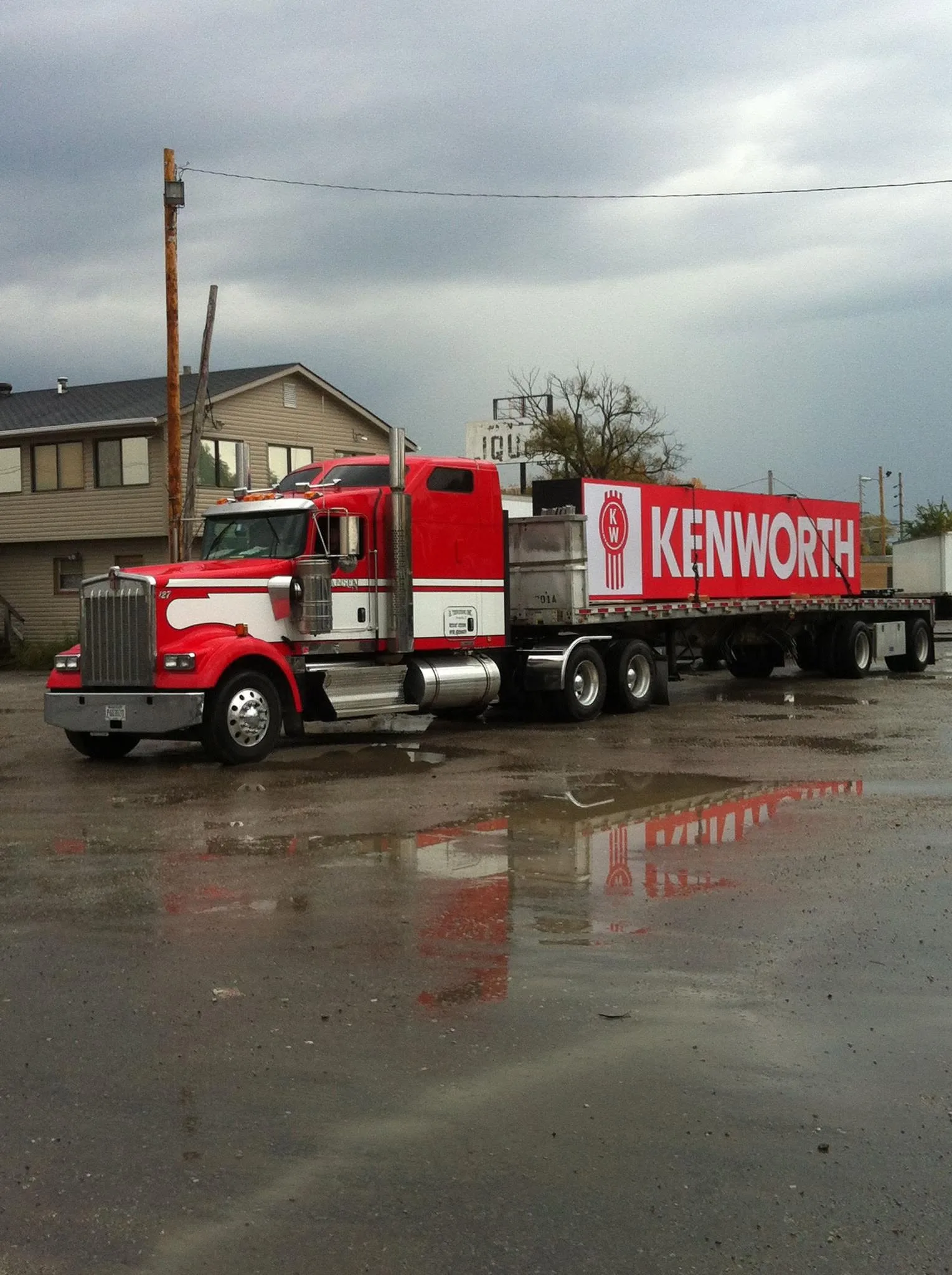 Red Hansen Kenworth W-900 hauling a KENWORTH ad in the rain